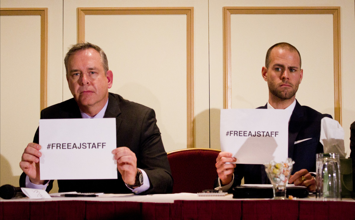 Owen Watson, executive producer for news at Al Jazeera English & Tom Henheffer, executive director of Canadian Journalists for Free Expression hold up #FreeAJStaff signs at a press conference in Toronto on Feb. 6. Photo: Preeteesh Peetabh Singh/The Dialog