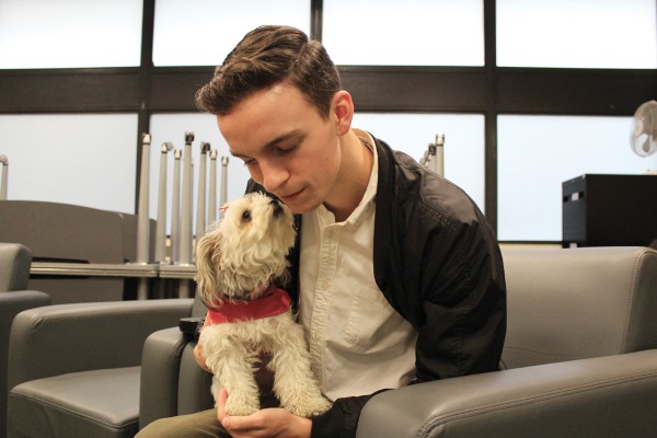 Patrick Strangways cuddles a therapy dog with working with St. John Ambulance at Casa Loma campus. Photo by Brittany Barber/The Dialog
