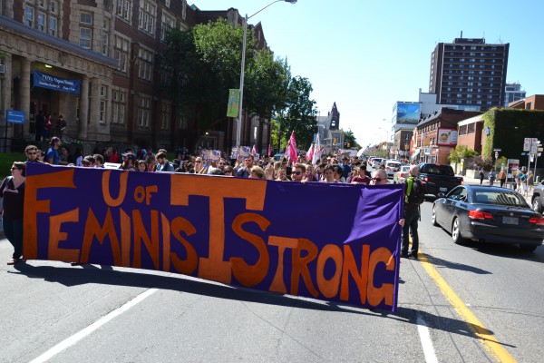 Image of group of University of Toronto students marching on streets with banner printed as "U of T Feminists Strong"