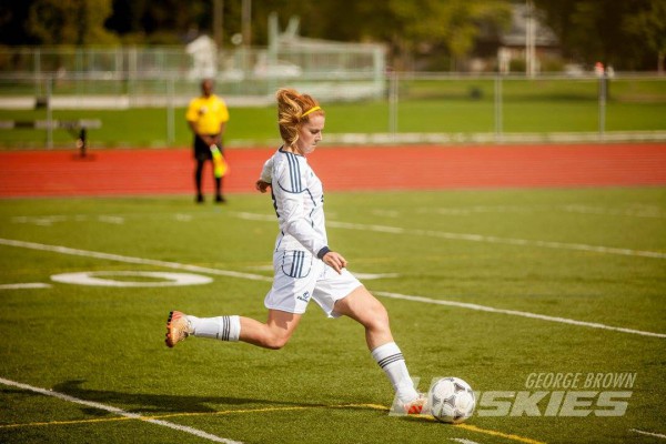 Image of Chelsea Fraser playing on field kicking the ball, she is a player on George Brown’s women’s soccer team this semester