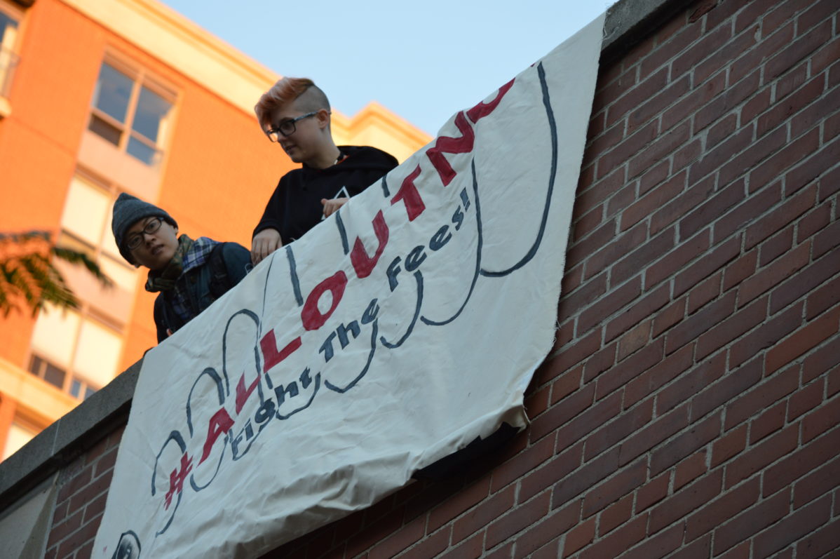 "Members of the Community Action Centre unfurl a large banner in support of the Fight the Fees! Campaign" Photo: Malcolm Derikx / The Dialog