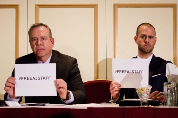 Owen Watson, executive producer for news at Al Jazeera English & Tom Henheffer, executive director of Canadian Journalists for Free Expression hold up #FreeAJStaff signs at a press conference in Toronto on Feb. 6. Photo: Preeteesh Peetabh Singh/The Dialog