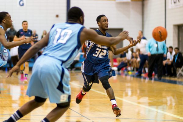Huskies guard Dennis Johnson passes the ball in a 99-89 loss against Sheridan College on Feb. 27. Photo: Brittany Barber/The Dialog