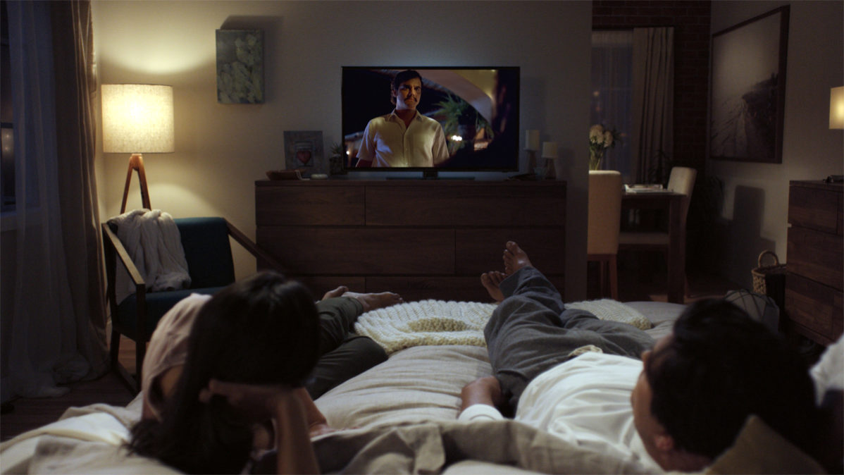 Photo of two poeple on a bed wathing a TV courtesy of Netflix